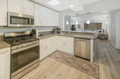 a kitchen with white cabinets and stainless steel appliances at Sunlit Shores beachside Bliss in San Diego