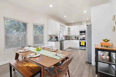 a kitchen with white cabinets and a wooden table at Catch n' Relax on Nimitz- Minutes from the Harbor in San Diego