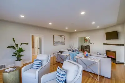 a living room with white furniture and a flat screen tv at Ultimate Getaway: Spa Game Rooms Firepit Views in San Diego