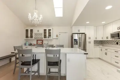 a kitchen with white cabinets and a kitchen island with chairs at Pristine Poway Retreat in Poway