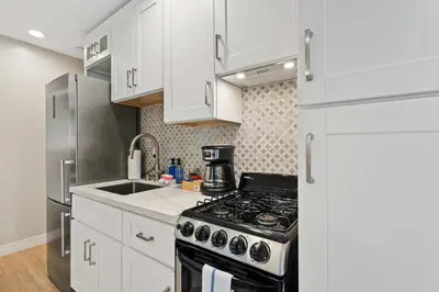 a kitchen with white cabinets and a stove top oven at Endless Summer Beach Studio - Beach - AC - Shops in San Diego