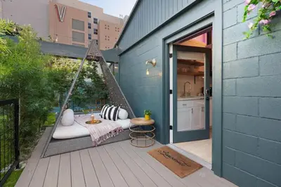 a porch with a swing with a table and a kitchen at Quaint Studio for 2 in the Heart of Little Italy in San Diego
