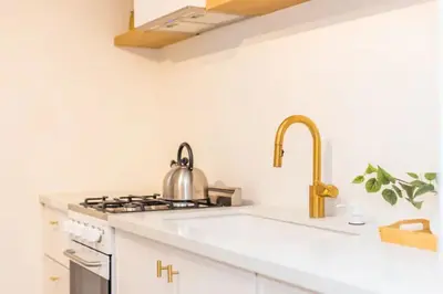 a white kitchen with a sink and a stove at Lovely Studio in the Heart of Little Italy in San Diego