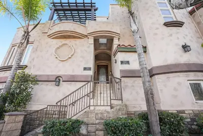 a house with palm trees in front of it at Steps to the boardwalk & beach with AC, WiFi, spacious deck, prime location in San Diego