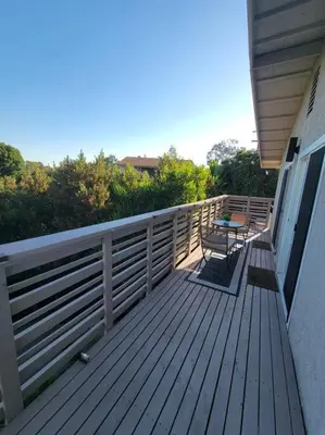a deck with a table and chairs on a house at San Diego Oasis with Hot Tub, Gym, Outdoor Theater, Huge Yard in San Diego