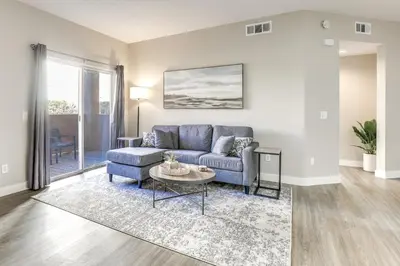 a living room with a blue couch and a table at Sunny San Diego Condo with Pool Access Near Wineries in San Diego