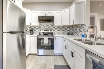 a kitchen with white cabinets and a stainless steel refrigerator at Sunny San Diego Condo with Pool Access Near Wineries in San Diego