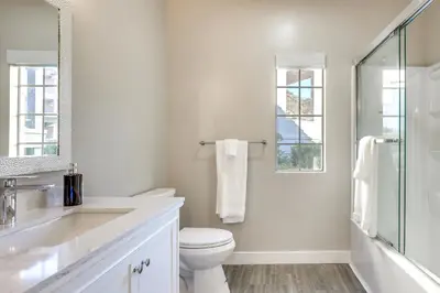 a white bathroom with a toilet and a sink at Sunny San Diego Condo with Pool Access Near Wineries in San Diego