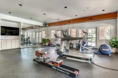 a gym with two tread machines and a flat screen tv at Sunny San Diego Condo with Pool Access Near Wineries in San Diego