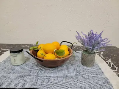 a bowl of lemons on a table with a candle and a plant at Exotic Gem Relaxing Farm Vibes Near Safari Zoo, Legoland & Wineries in Escondido