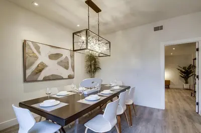 a dining room table with white chairs and a chandelier at Lux Escape 2 • Views Hot Tub Games Mini Golf in San Diego