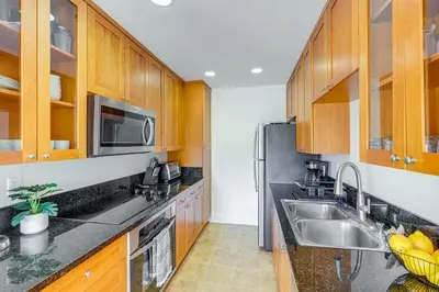 a kitchen with wooden cabinets and a stainless steel refrigerator at San Diego Condo with Pool Access about 2 Mi to Beach! in San Diego