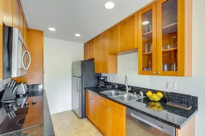 a kitchen with wooden cabinets and a stainless steel refrigerator at San Diego Condo with Pool Access about 2 Mi to Beach! in San Diego