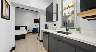 a kitchen with a sink and a bedroom with a bed at Balboa Park Hotel Downtown Little Italy in San Diego