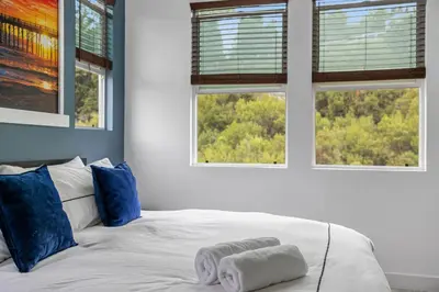 a white bed with blue pillows and two windows at Better Two-Gether 2-bed 2,5-bath in Oceanside