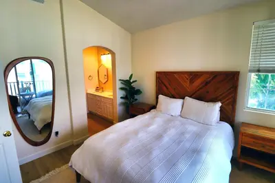 a bedroom with a large bed and a mirror at Sweet Pea Place, 2 bed with pool in Encinitas