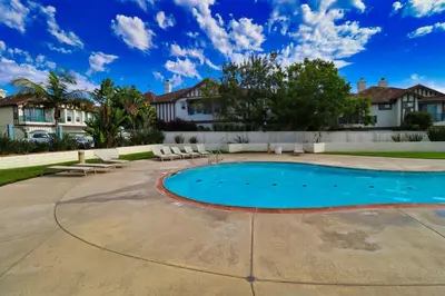 a swimming pool in a yard with chairs and houses at Sweet Pea Place, 2 bed with pool in Encinitas