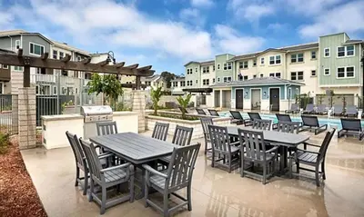 a patio with tables and chairs and buildings at Makena By The Sea, 3 bed home near beach in Oceanside