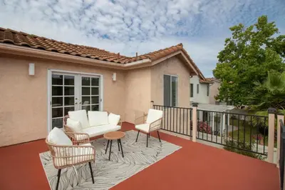 a patio with a white couch and chairs on a balcony at Sunset Views Retreat in Vista