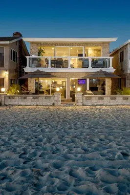 a house on the beach at night with a sand floor at Oceanfront 3BR Home with Pool Table & Patio in Newport Beach