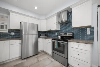 a kitchen with white cabinets and a stainless steel refrigerator at Stunning Casa Surf House in Newport with Parking Stunning Casa Surf House in Newport in Newport Beach