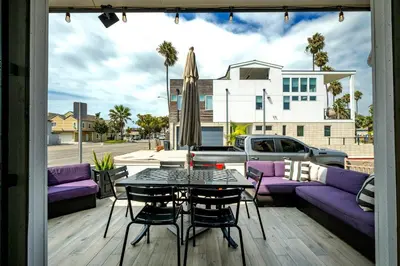 a patio with a purple couch and a table and chairs at Giant Newport Duplex - Surf, Sand, Playground, Parking in Newport Beach