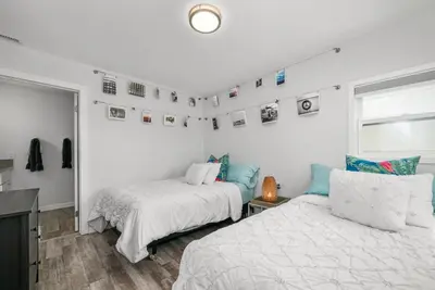 a bedroom with two beds and pictures on the wall at Giant Newport Duplex - Surf, Sand, Playground, Parking in Newport Beach
