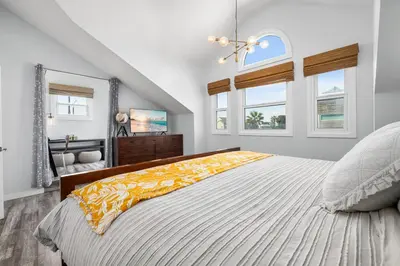 a bedroom with a large bed and two windows at Giant Newport Duplex - Surf, Sand, Playground, Parking in Newport Beach