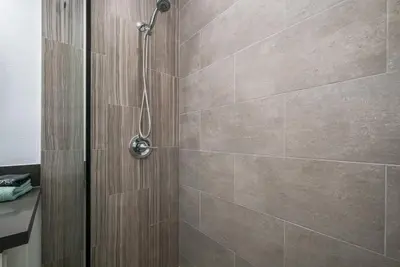 a bathroom with a shower with brown tile at Perfect Surf Casa in Newport Near Beach and Pier in Newport Beach