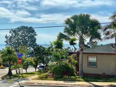 a street with palm trees and a house with a stop sign at Rustic Coastal Retreat in Sunset Cliffs three beds & two baths in San Diego