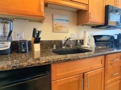 a kitchen with wooden cabinets and a sink at Ocean, Bay, Downtown, and City view Condo, Few steps from the ocean in San Diego