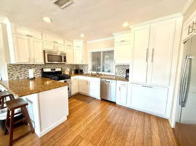 a kitchen with white cabinets and a wooden floor at The Cozy Ranch Retreat in San Diego