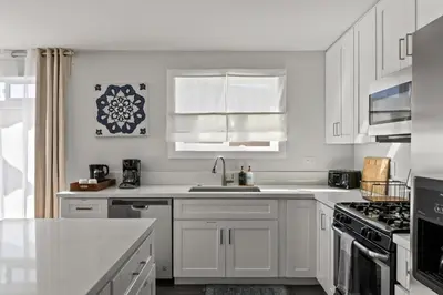 a white kitchen with white cabinets and a sink at Beach Abode Walk to the Ocean in San Diego