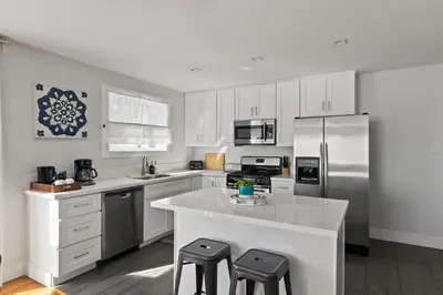 a kitchen with white cabinets and a large island with stools at 6 Bedroom Family Getaway Walk to Law Street Beach in San Diego
