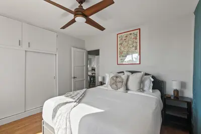 a bedroom with a white bed with a ceiling fan at 6 Bedroom Family Getaway Walk to Law Street Beach in San Diego
