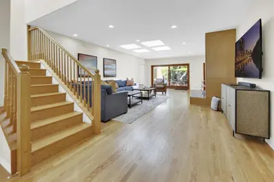 a living room with a staircase with a couch and a table at Pacific Views Retreat - Rooftop Deck, Game Room, Fire Pit & Cozy Backyard! in San Diego