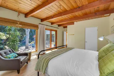 a bedroom with a bed and a chair and a window at Pacific Views Retreat - Rooftop Deck, Game Room, Fire Pit & Cozy Backyard! in San Diego