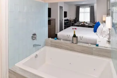 a bathroom with a bath tub and a bed at Holiday Inn Express & Suites San Diego - Mission Valley by IHG in San Diego