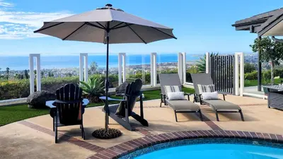 a patio with chairs and an umbrella next to a pool at Ocean Views Beach House - 40 PCT Off Monthly in San Clemente