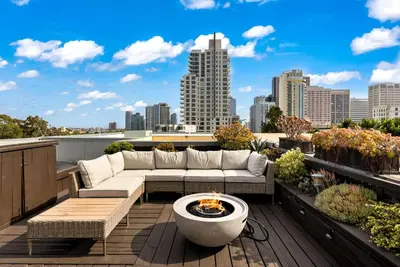a rooftop patio with a couch and a fire pit at City Lights and Rooftop Nights by Rather Be Properties in San Diego