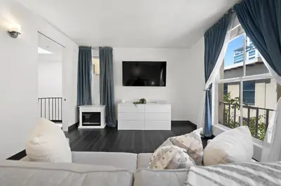a living room with a white couch and a tv at City Lights and Rooftop Nights by Rather Be Properties in San Diego