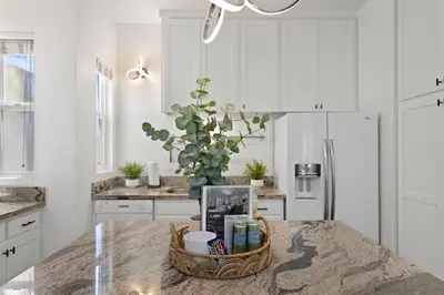 a kitchen with white cabinets and a table with a basket at City Lights and Rooftop Nights by Rather Be Properties in San Diego