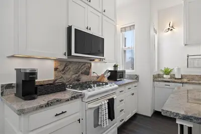 a white kitchen with a stove and a microwave at City Lights and Rooftop Nights by Rather Be Properties in San Diego