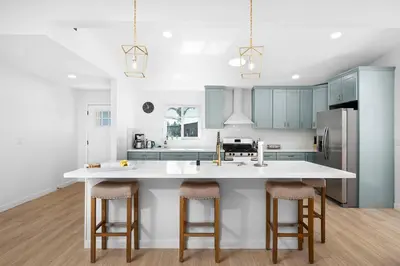a kitchen with blue cabinets and a large island with bar stools at NEW CA Coastal Beauty 6 mins to Imperial Beach in San Diego