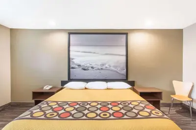 a hotel room with a bed with a picture on the wall at Super 8 by Wyndham National City Chula Vista in National City