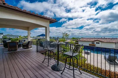 a deck with chairs and a table and a fence at Spanish Dream with Ocean Views in Encinitas