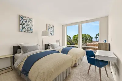 two beds in a white room with a window at Sea Serenity Coastline Views and Pool in San Diego