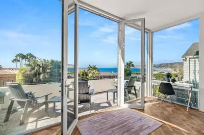 a living room with glass doors and a view of the ocean at Sea Serenity Coastline Views and Pool in San Diego