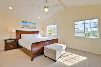 a bedroom with a bed and a chair and windows at Beach Happy in San Diego