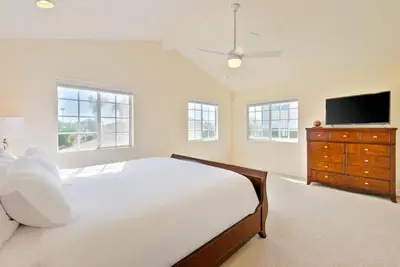 a white bedroom with a large bed and a flat screen tv at Beach Happy in San Diego
